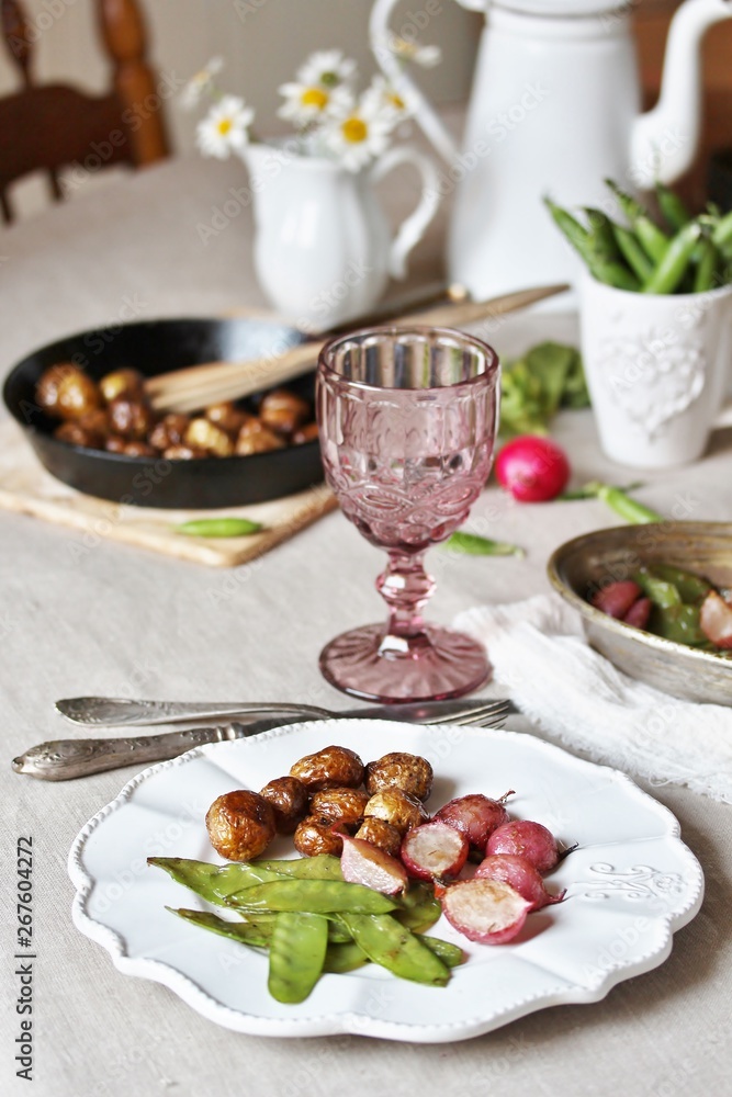 young summer vegetables-fried radish, young peas and young potatoes. dinner served at the table, beautiful table setting. young summer vegetables-fried radish, young peas and young potatoes. dinner served at the table, beautiful table setting.