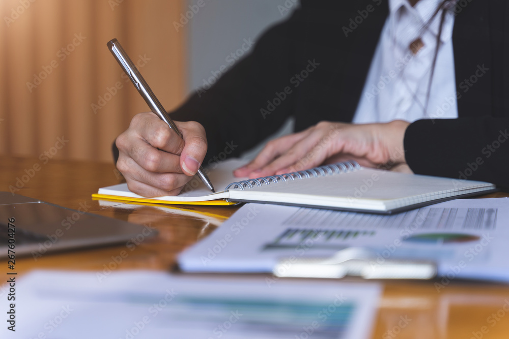 Businesswoman or Secretary holding silver pen ready to make note in opened notebook sheet. Business finances and Secretary concept. Businesswoman or Secretary holding silver pen ready to make note in opened notebook sheet. Business finances and Secretary concept.