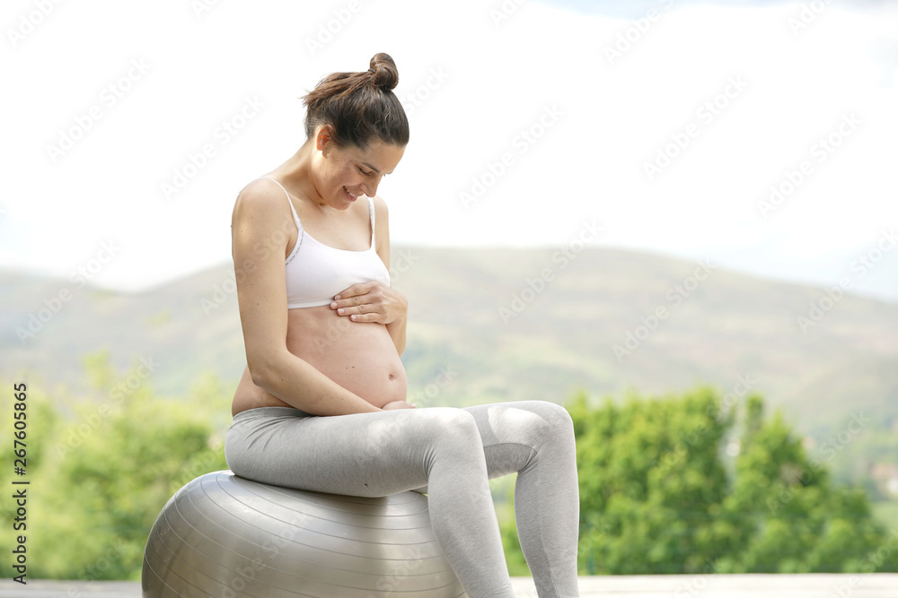 Pregnant woman doing yoga exercises on fitness ball