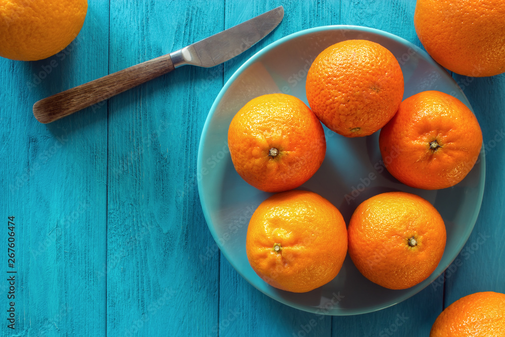 Ripe clementines and oranges with knife on rustic turquoise wooden table with copy space , top view
