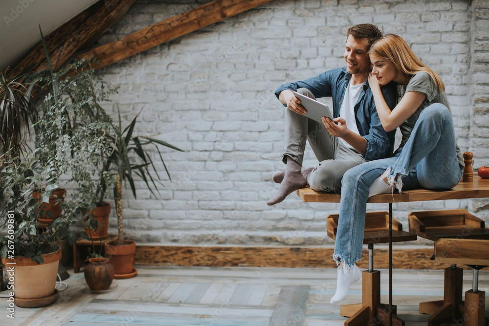Young couple is using a digital tablet and smiling in kitchen at home Young couple is using a digital tablet and smiling in kitchen at home