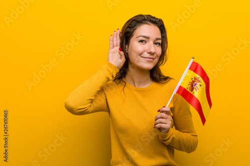 Young european woman holding a spanish flag trying to listening a gossip.
