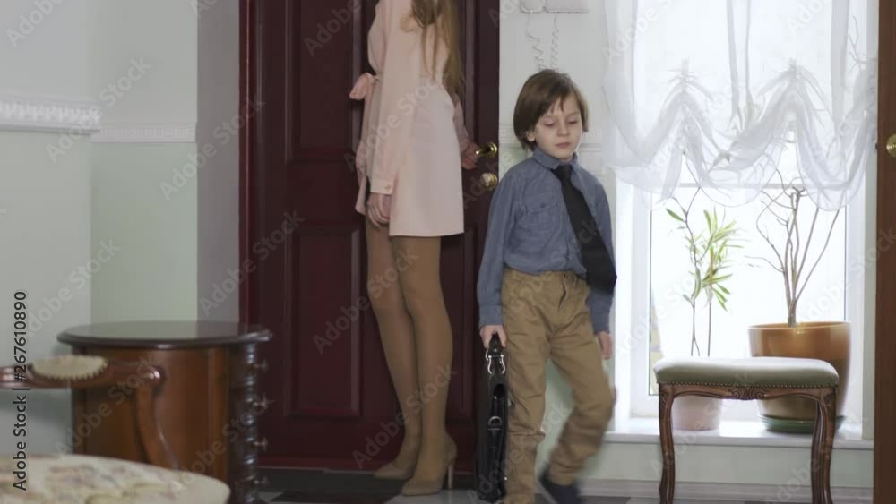 Young girl open a door and come inside home with tired small brother who carring big schoolbag Young girl open a door and come inside home with tired small brother who carring big schoolbag