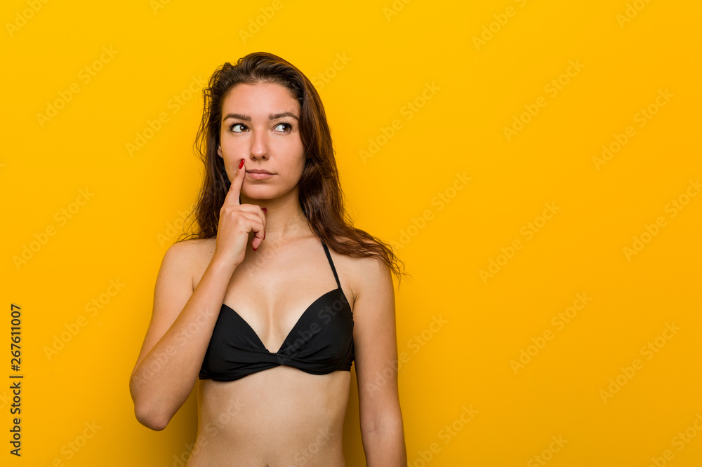 Young european woman wearing bikini looking sideways with doubtful and skeptical expression.
