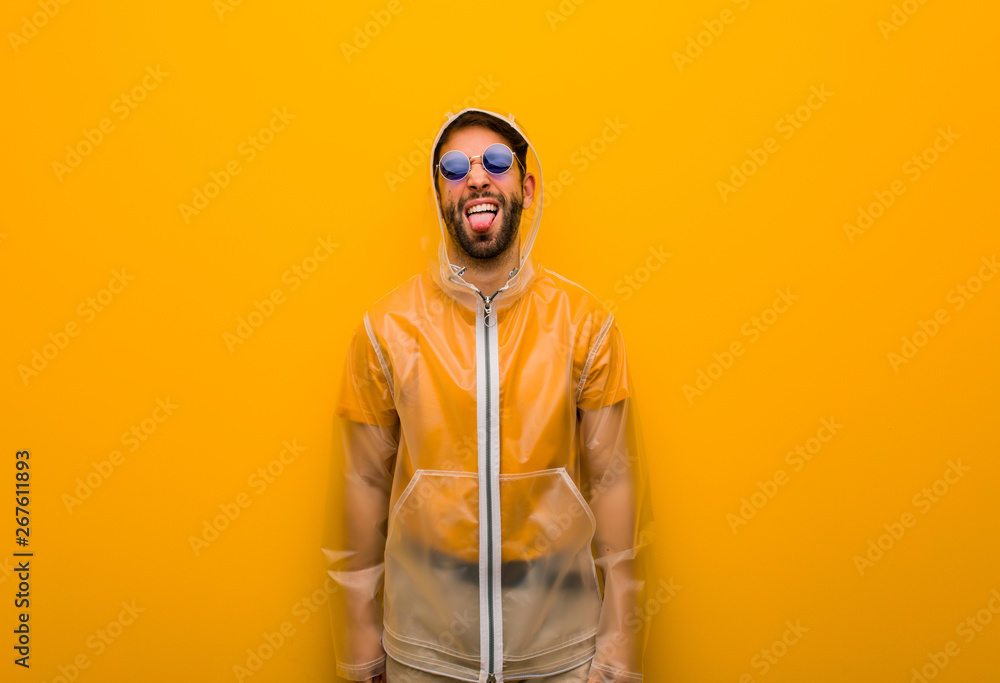 Young man wearing a rain coat funnny and friendly showing tongue Young man wearing a rain coat funnny and friendly showing tongue