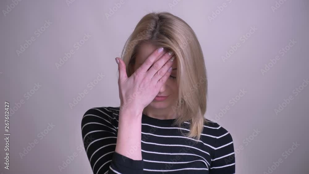 Closeup portrait of adult attractive blonde caucasian female making a face palm with embarrassment looking at camera with background isolated on white Closeup portrait of adult attractive blonde caucasian female making a face palm with embarrassment looking at camera with background isolated on white