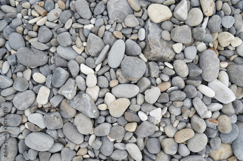 Texture of gray oval pebble stones next to the sea. Close-up