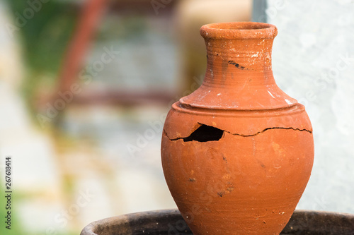 Broken clay jug with large hole and crack.