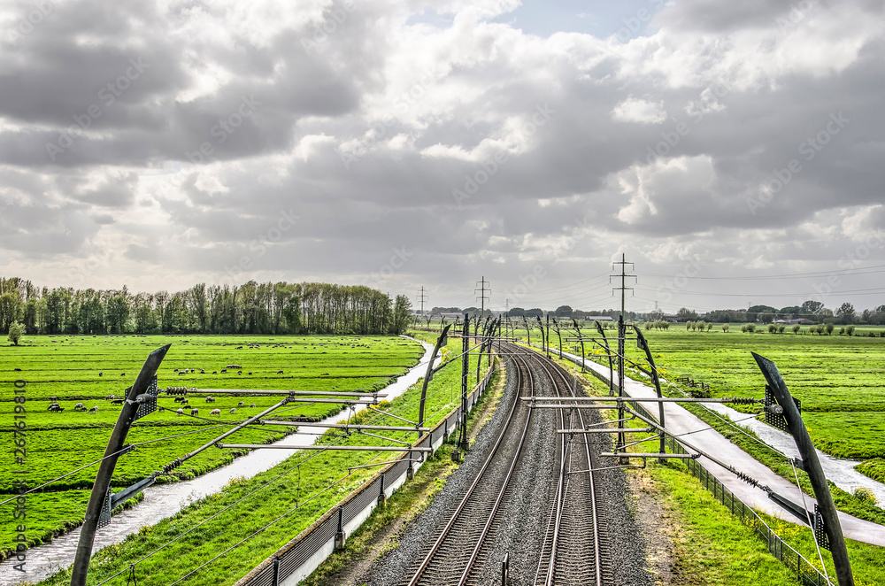 Betuwelijn cargo railway line through a polder landscape  in Alblasserwaard, The Netherlands under a cloudy sky