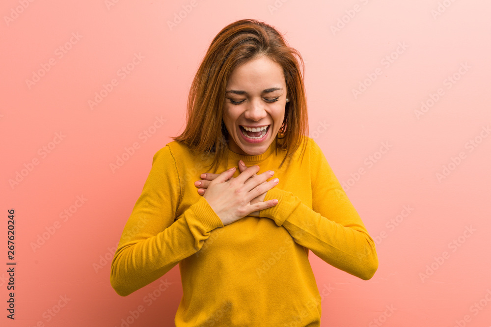 Fototapeta premium Young pretty young woman laughing keeping her hands on heart, concept of happiness.