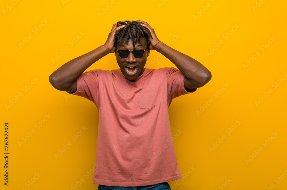 Young casual black man wearing sunglasses laughs joyfully keeping hands on head. Happiness concept. Young casual black man wearing sunglasses laughs joyfully keeping hands on head. Happiness concept.