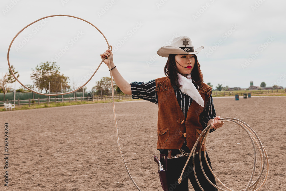 pretty Chinese cowgirl throwing the lasso in a horse paddock Stock Photo