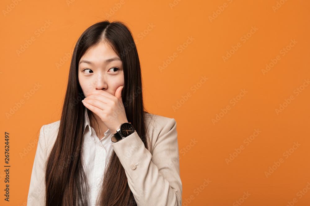 Young business chinese woman thoughtful looking to a copy space covering mouth with hand. Young business chinese woman thoughtful looking to a copy space covering mouth with hand.