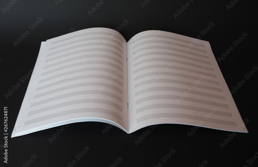 Blank music sheet book for writing notes isolated on black background