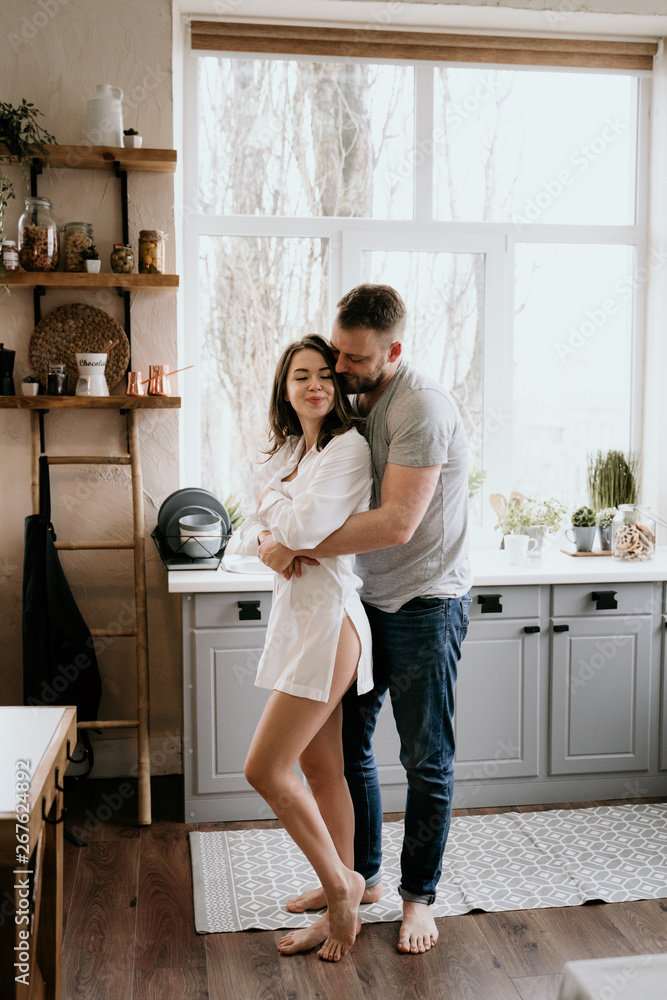 Romantic young couple cooking together in the kitchen. The girl in the white shirt. Breakfast together. Romantic young couple cooking together in the kitchen. The girl in the white shirt. Breakfast together.