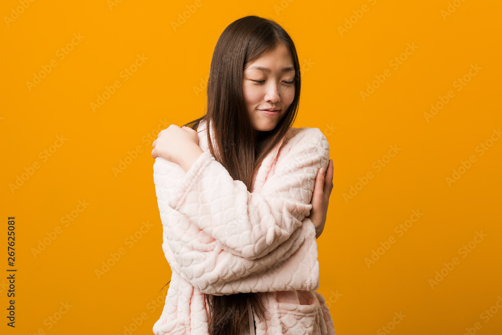 Young chinese woman in pajama hugs himself, smiling carefree and happy. Young chinese woman in pajama hugs himself, smiling carefree and happy.
