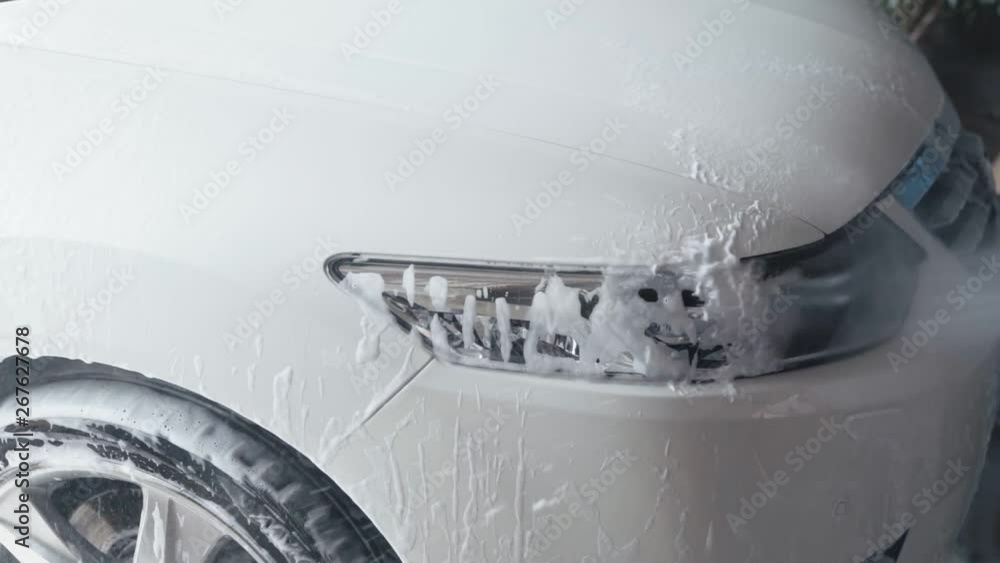 Car washing process. Jet of water with high pressure clean off car from