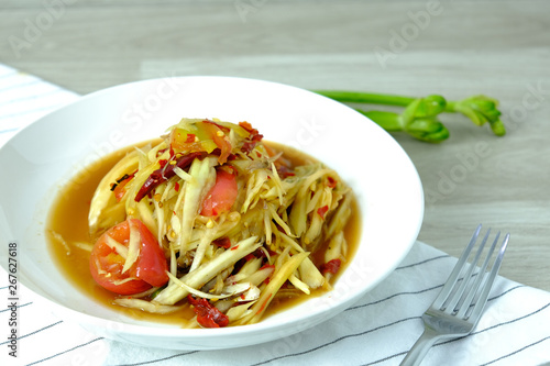 Papaya Salad with Crab. Thai food cuisine menu “Somtum”. It’s tasty, Spicy, Sour and Salty. Famous in Thailand and Lao. Close up Dish with fork on wooden background.