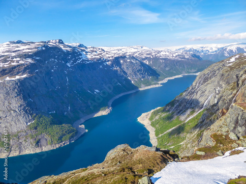 A panoramic view from above on a fjord-like Ringedalsvatnet lake, Norway . Snow-capped mountains. Spring slowly coming to the higher parts of the mountains. Water of the lake has a navy blue shade.