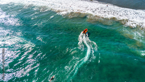 Rescue boat rushing to the shore on a local beach on sunny day. Muriwai Beach, Auckland, New Zealand