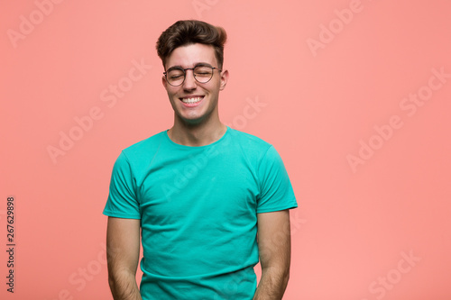 Young cool caucasian man laughs and closes eyes, feels relaxed and happy.