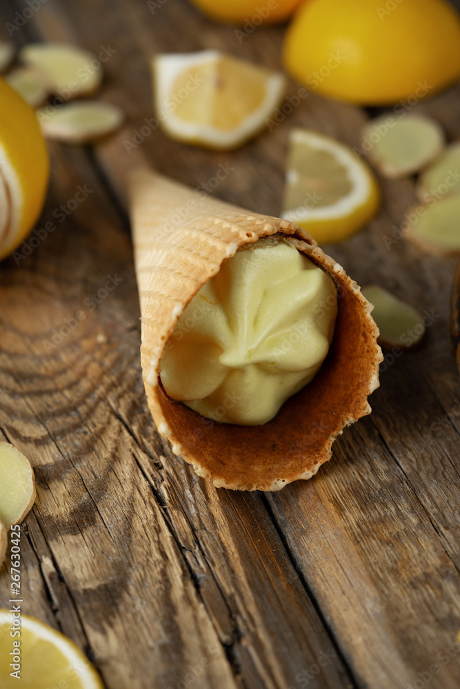 ginger lemon ice cream in a waffle cone with fresh lemons and ginger slices on a dark wooden background of boards ginger lemon ice cream in a waffle cone with fresh lemons and ginger slices on a dark wooden background of boards