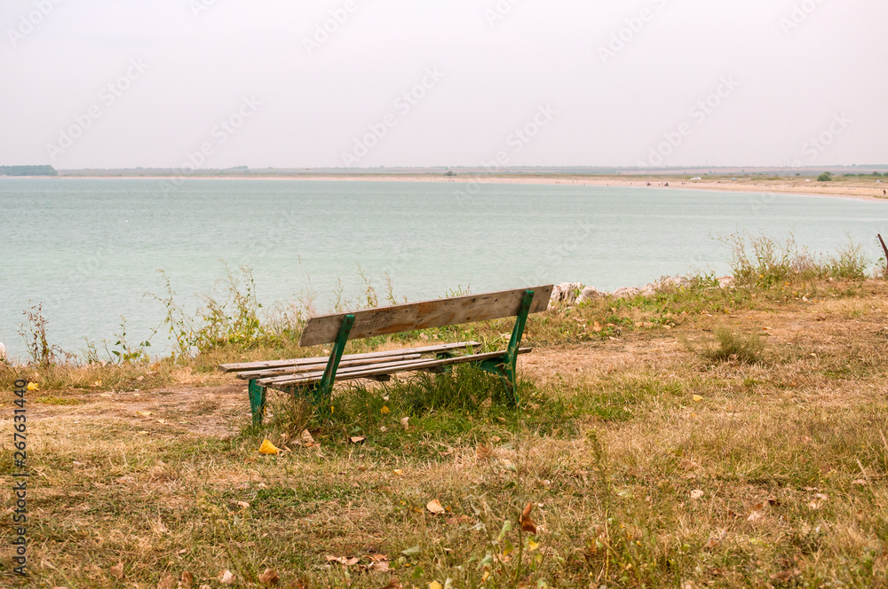 Lonely empty wooden obsolete vintage bench on the seashore