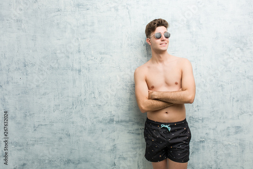 Foto Young caucasian man wearing swimsuit smiling confident with crossed arms
