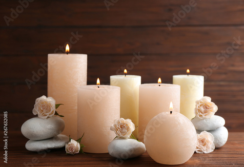 Composition of burning candles, spa stones and flowers on table. Space for text