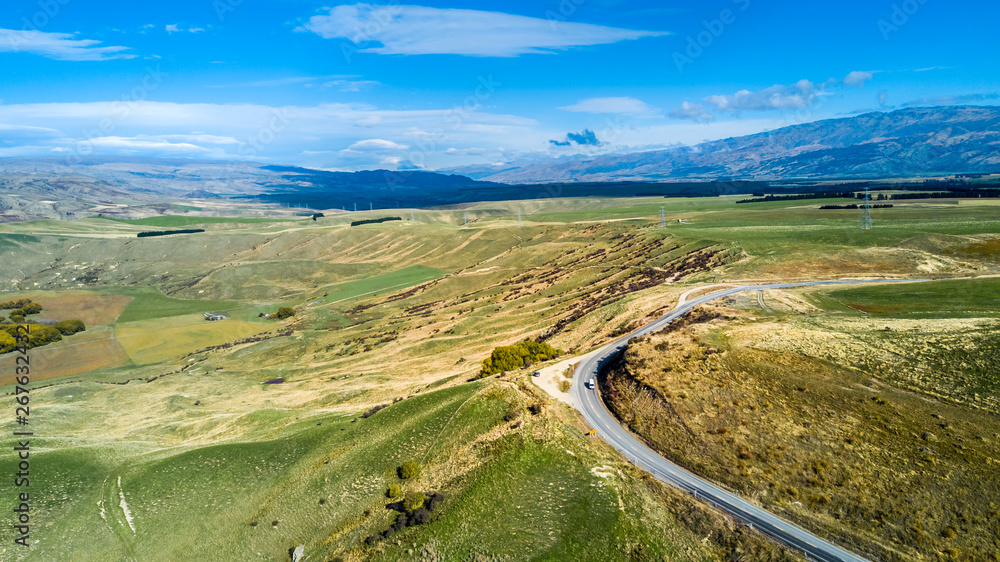 Naklejka premium Road running through hills and farmland. Otago, South Island, New Zealand