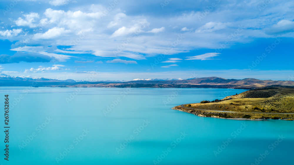 Hills on a shore of a beautiful lake with mountain range on the background. Otago, South Island, New Zealand Hills on a shore of a beautiful lake with mountain range on the background. Otago, South Island, New Zealand