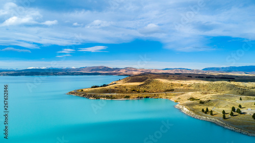Hills on a shore of a beautiful lake with mountain range on the background. Otago, South Island, New Zealand