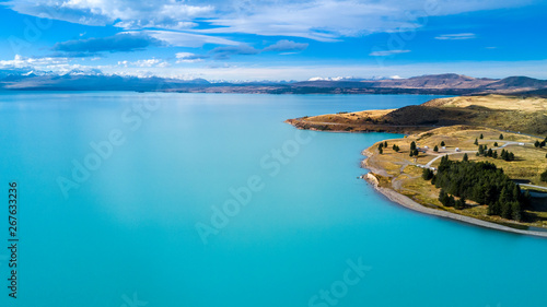 Hills on a shore of a beautiful lake with mountain range on the background. Otago, South Island, New Zealand