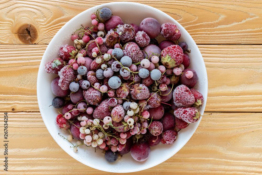 frozen berries, black currant, red currant, raspberry, blueberry in bowl decorated by currant leaf on wooden table in rustic style, top view. frozen berries, black currant, red currant, raspberry, blueberry in bowl decorated by currant leaf on wooden table in rustic style, top view.