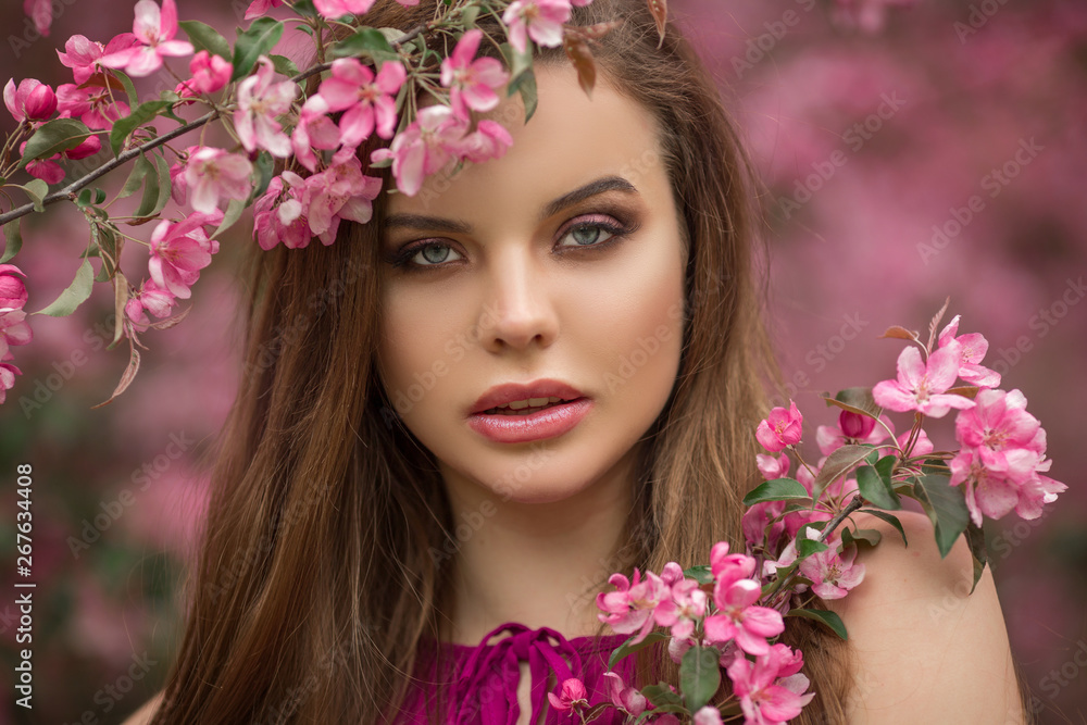 Closeup romantic portrait of young beautiful woman in blossom apple garden with pink flowers