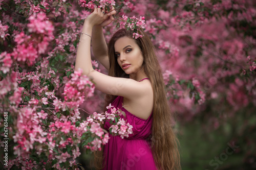 Beautiful girl in blossom apple garden with pink flowers  spring time