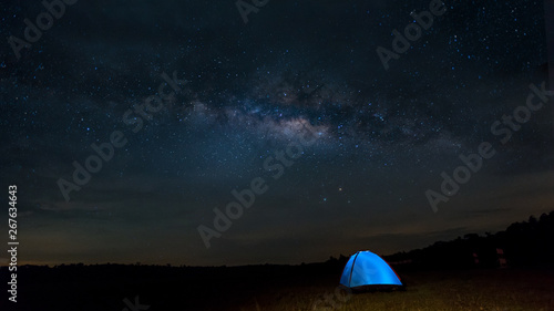 Camping under the stars. The Milky Way stretches overhead a blue tent high In the pasture .