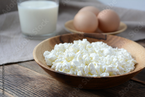 Cottage cheese in a wooden bowl, milk in a glass, eggs. Farm products. Village Breakfast