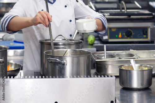 Chef tastes food. Kitchen utensils  plate with metal pots lids and scoops. Concept violation conditions and shelf life products  sanitary inspection