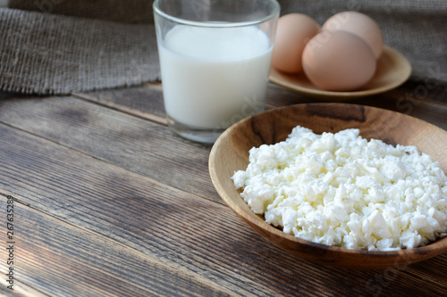 Cottage cheese in a wooden bowl, milk in a glass, eggs. Farm products. Village Breakfast