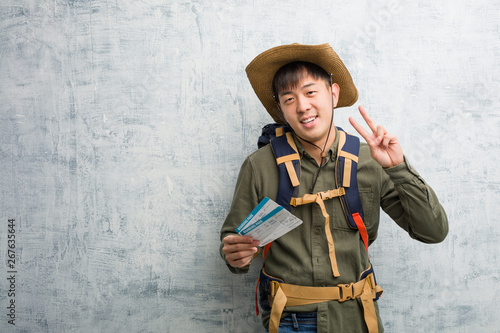 Young explorer chinese man holding an air tickets showing number two