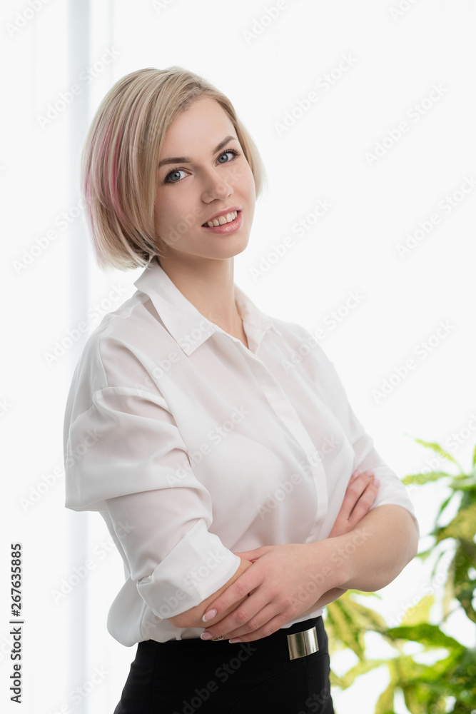 Young beautiful blonde girl with short hair in a white shirt is standing in the office. Young beautiful blonde girl with short hair in a white shirt is standing in the office.