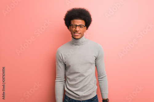 Young african american man over a pink wall winking, funny, friendly and carefree gesture
