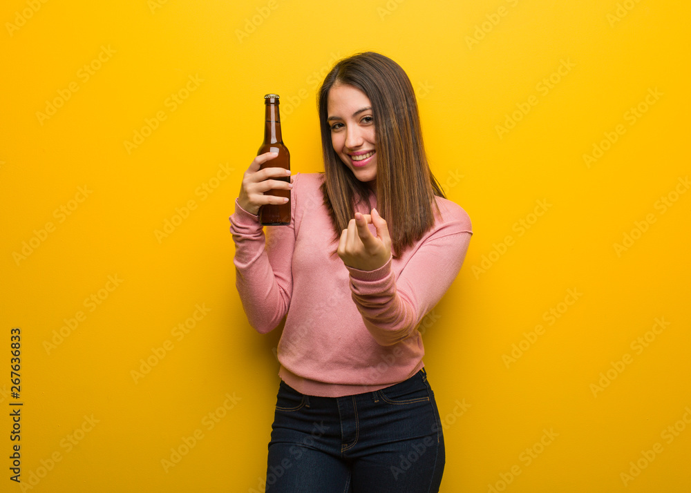 Young cute woman holding a beer inviting to come Young cute woman holding a beer inviting to come