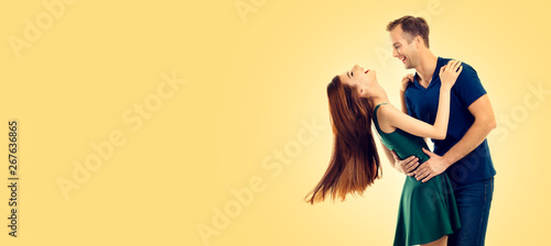 Photo of young happy dancing or hugging couple, with copy space, over yellow ...