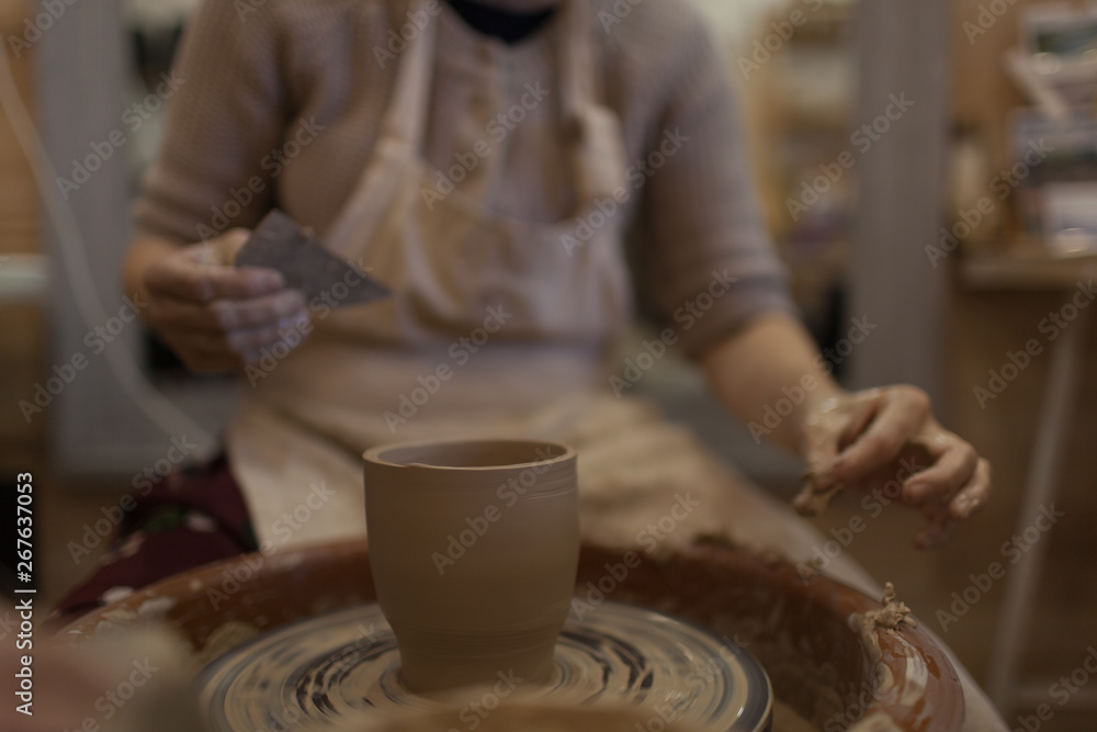 Potter working on potters wheel making ceramic pot from clay in pottery workshop Potter working on potters wheel making ceramic pot from clay in pottery workshop