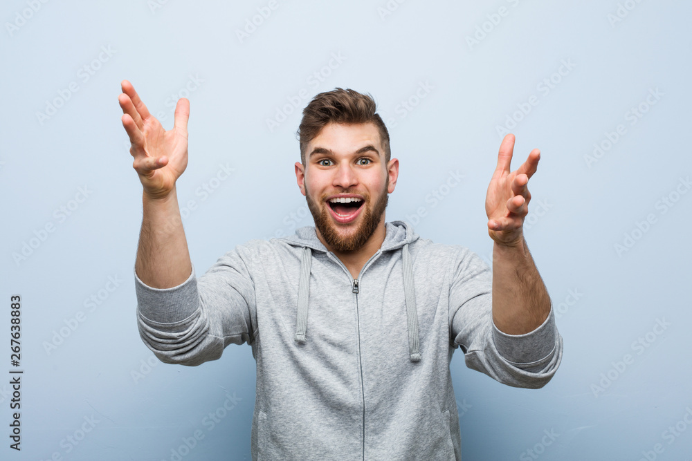 Young handsome fitness man receiving a pleasant surprise, excited and raising hands. Young handsome fitness man receiving a pleasant surprise, excited and raising hands.