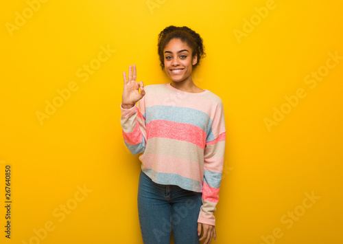 Young black african american girl with blue eyes cheerful and confident doing ok gesture