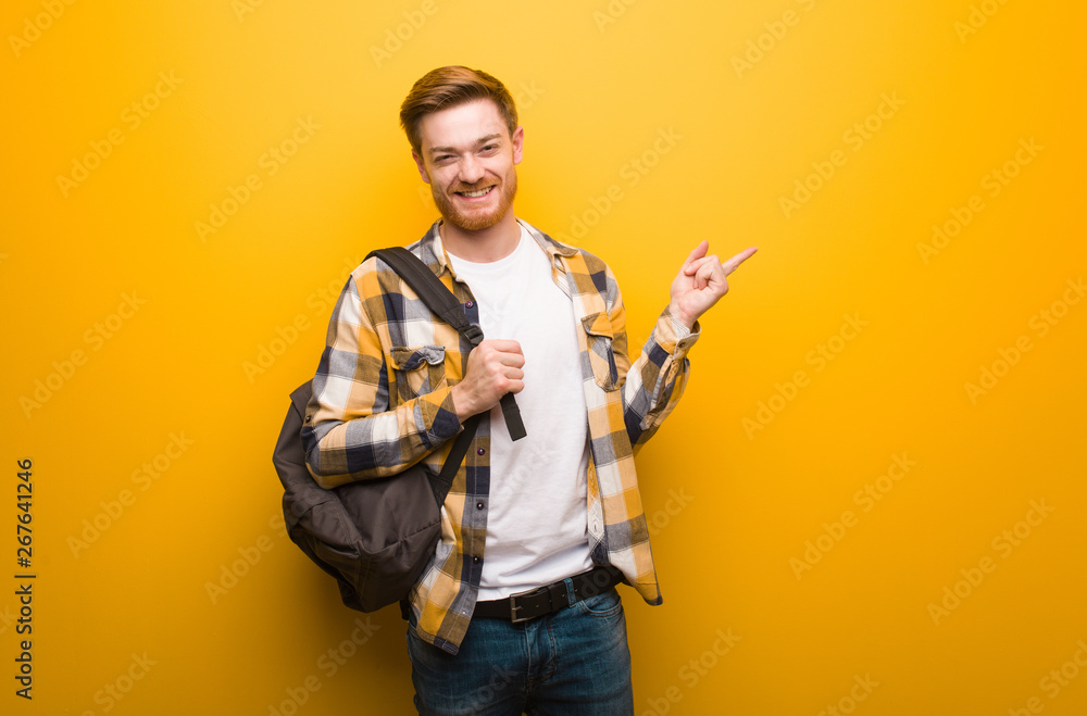 Young redhead student man pointing to the side with finger Young redhead student man pointing to the side with finger