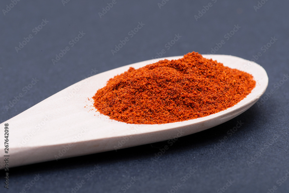Dried Organic Sweet Paprika powder in handmade wooden spoon on dark background. Seasoning Spice. Dried Organic Sweet Paprika powder in handmade wooden spoon on dark background. Seasoning Spice.